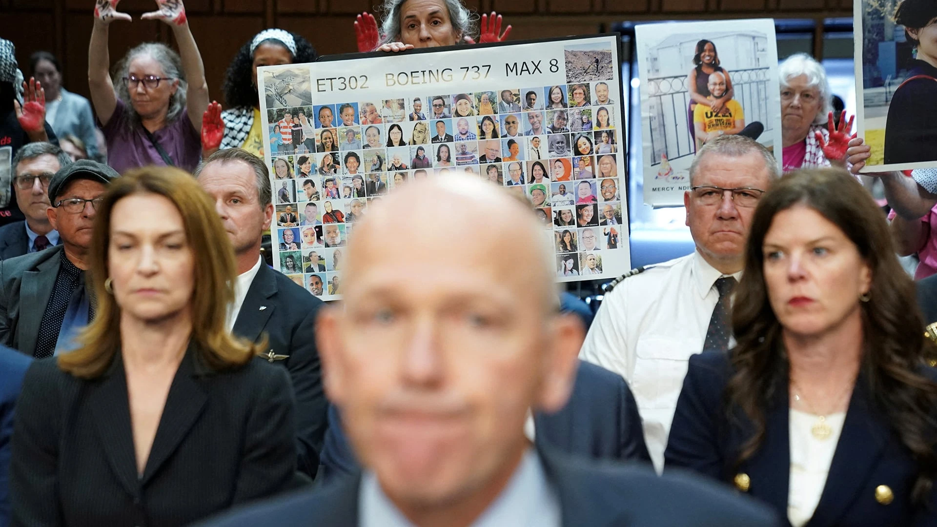 Плакат с фотографиями погибших на рейсе 302 авиакомпании Ethiopian Airlines на слушаниях в сенате США с участием руководства Boeing / Reuters / Kevin Lamarque