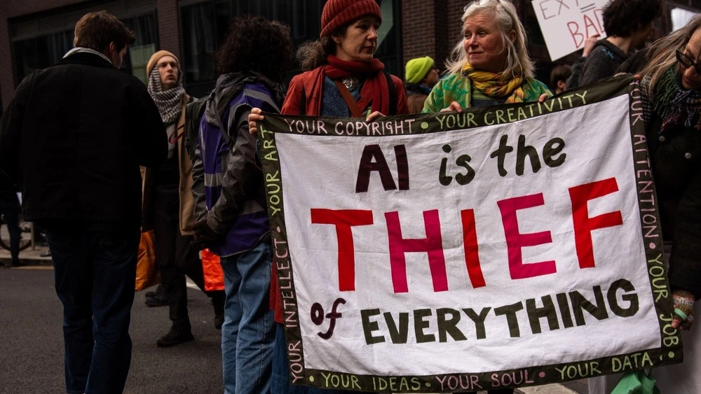A participant in the “March Against Cars” protest in London holding a sign that reads “AI—Thief of All Things” / Photo: Loredana Sangiuliano/Shutterstock.com